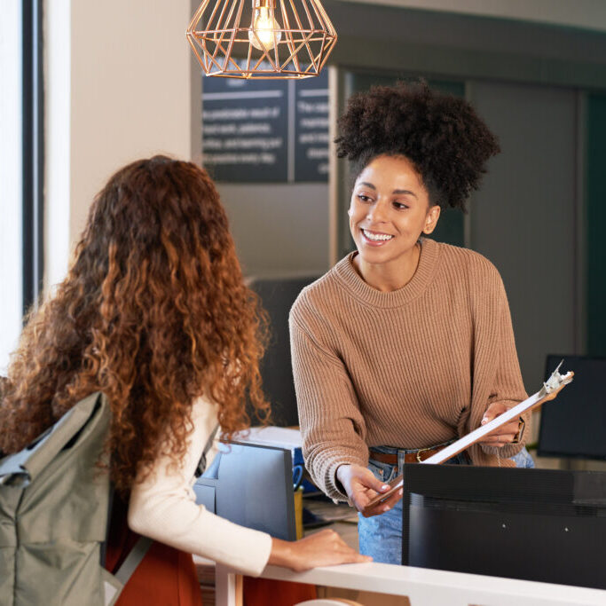 Young woman checks in at front desk, reception, hotel, college library admission. High quality photo