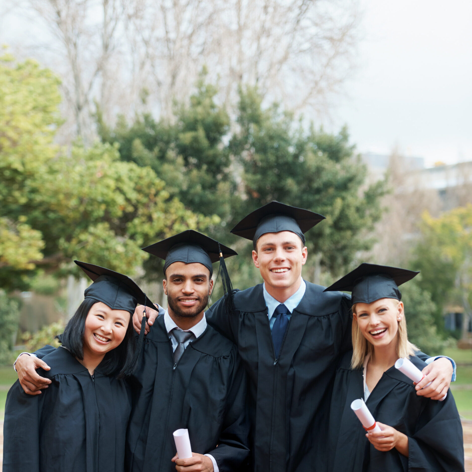 Theyve forged lifelong bonds. A group of college graduates standing in cap and gown and holding their diplomas